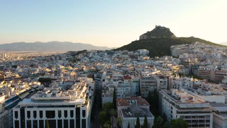 toma cinematográfica, vista aérea del monte lycabettus, edificio del parlamento y edificios residenciales al amanecer del verano en atenas, grecia