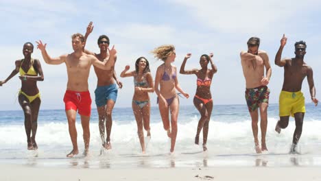 vista frontal de amigos de raza mixta corriendo juntos en la playa 4k