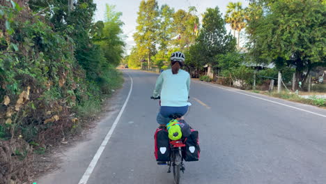 Una-Filmación-Dinámica-De-Una-Mujer-Que-Viaja-En-Bicicleta-Con-Alforjas-Y-Comestibles-En-La-Parte-Trasera