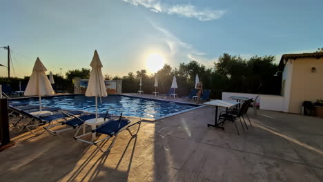 Woman-in-black-bikini-leaving-a-swimming-pool-at-sunset