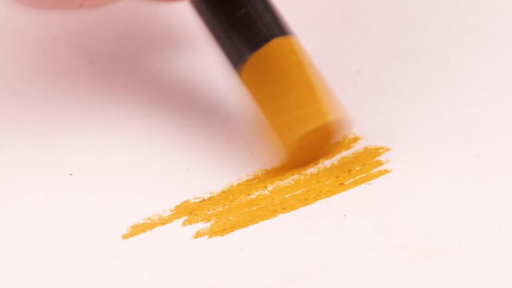 Drawing with a yellow mustard crayon on a piece of paper