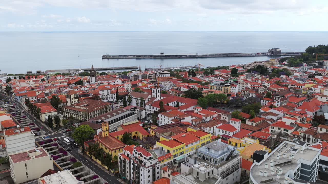 Aerial view of Funchal, Madeira, Portugal, showcasing the harbor and the characteristic orange roofs of the city buildings. Circle Dolly
