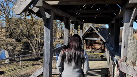 Young-woman-dark-hair-walking-in-rustic-wood-rural-setting-village-outdoor