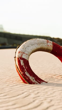 a red and white life preserver laying on the beach sand