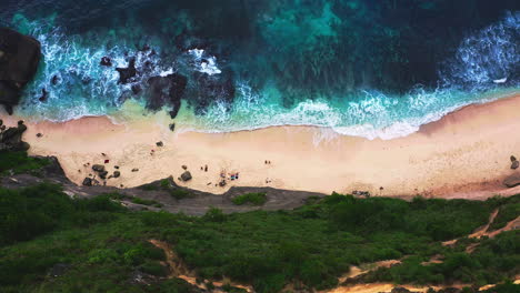 las olas azules espumosas del mar bañando la playa de diamantes debajo del acantilado rocoso