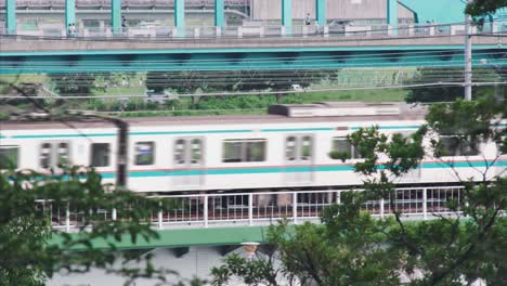 two jr trains passing by on the bridge in tamagawa at daytime in tokyo, japan