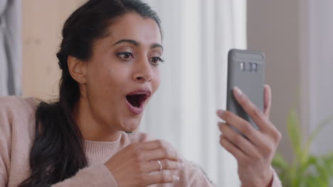 mujer hermosa que está chateando por video usando un teléfono inteligente hablando con un amigo pareciendo sorprendida disfrutando de la conversación en el teléfono móvil en casa