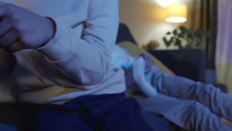 Close-Up-On-Hands-Of-Two-Young-Boys-At-Home-Playing-With-Computer-Games-Console-On-TV-Holding-Controllers-Late-At-Night-10