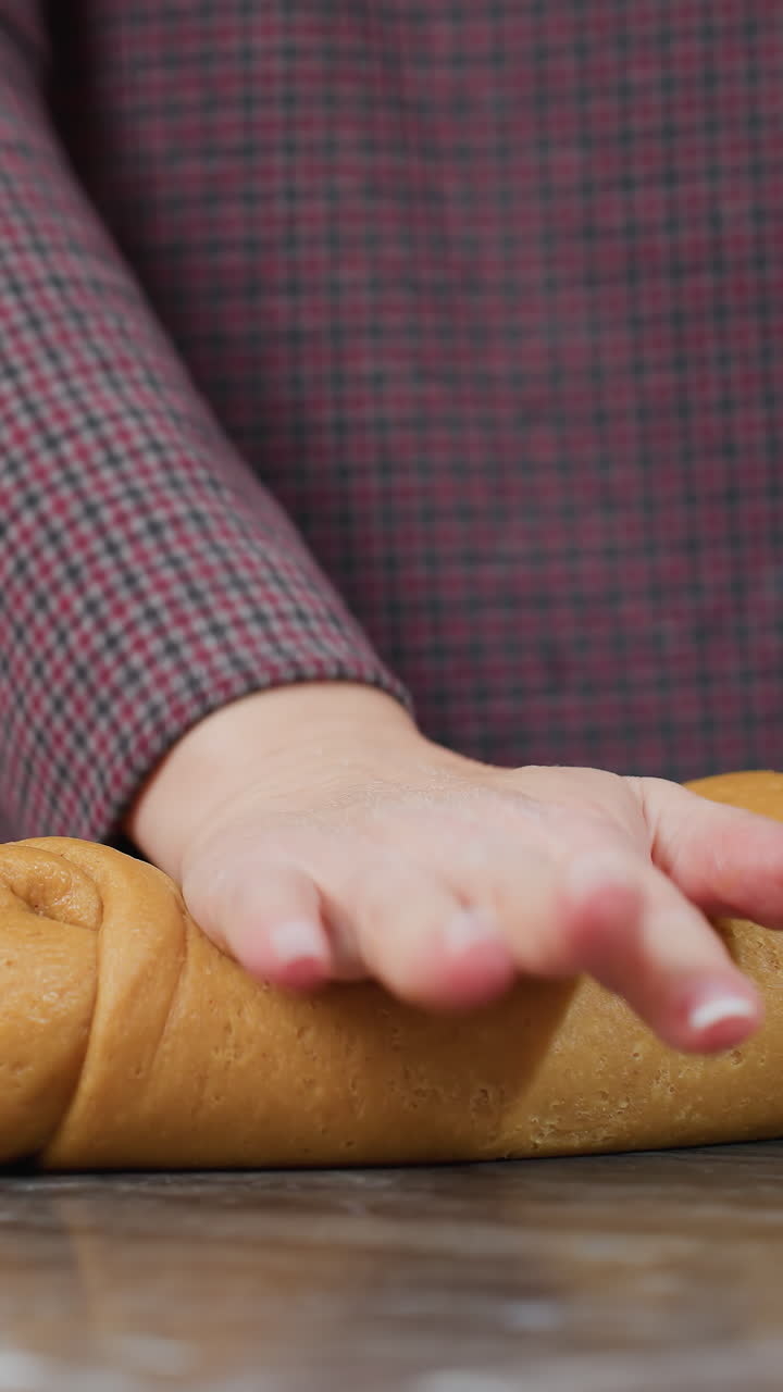 왼손에 팔를 고 있는 요리사의 부분적인 모습, 부 카운터에서 신선한 반죽을 조정하고 는 모습, 따뜻한 조명과 우아한 가전제품으로 현대 부에서 집에서 만든 베이킹 상품을 준비하는 모습