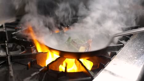 cooking and adding liquor to flambe vegetables in a pan - close up