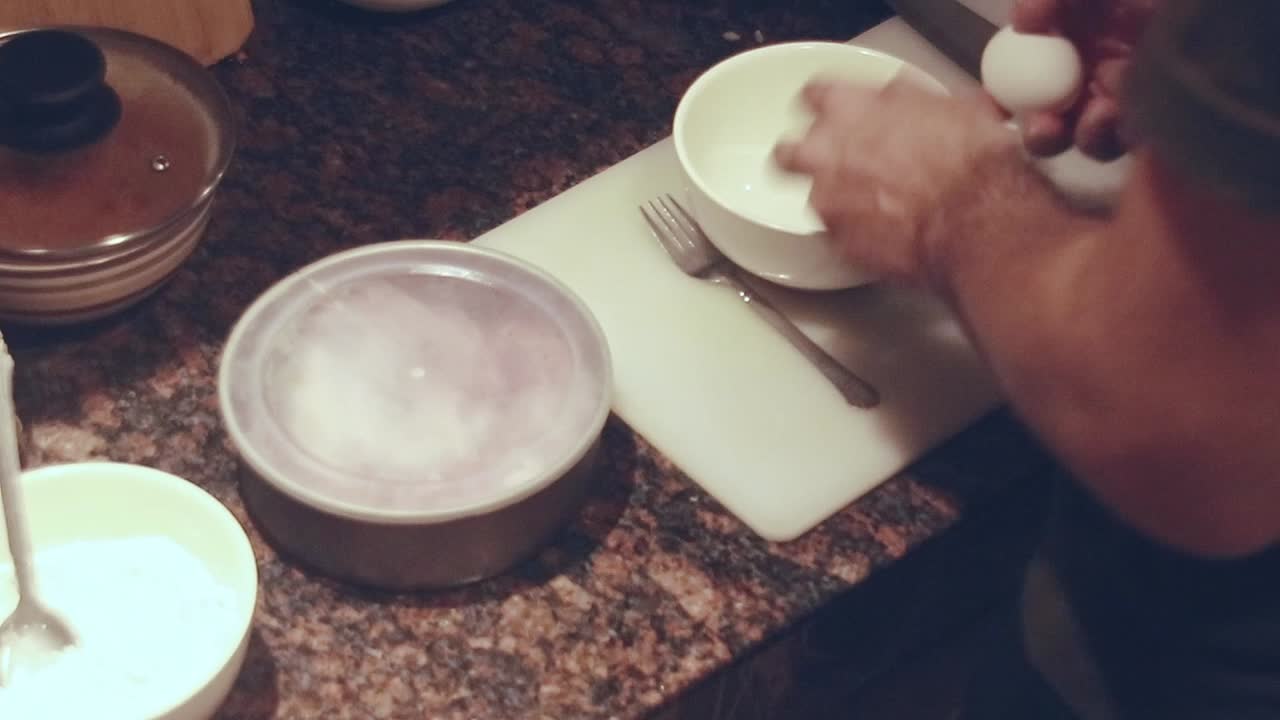 Overhead view of preparing batter for schnitzel on a marble kitchen counter, showing candid daily chores and home cooking