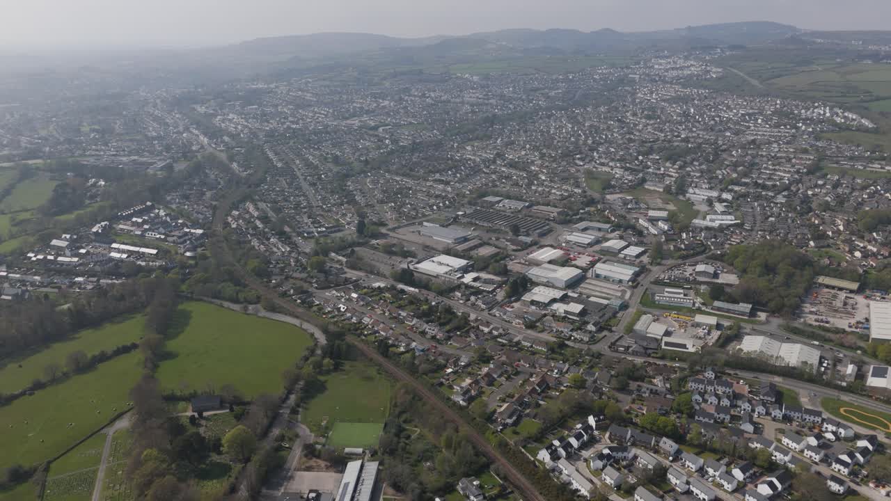 High aerial panorama of St Austell spreading across gentle hills with dense housing, retail centres, light industry and surrounding patchwork countryside