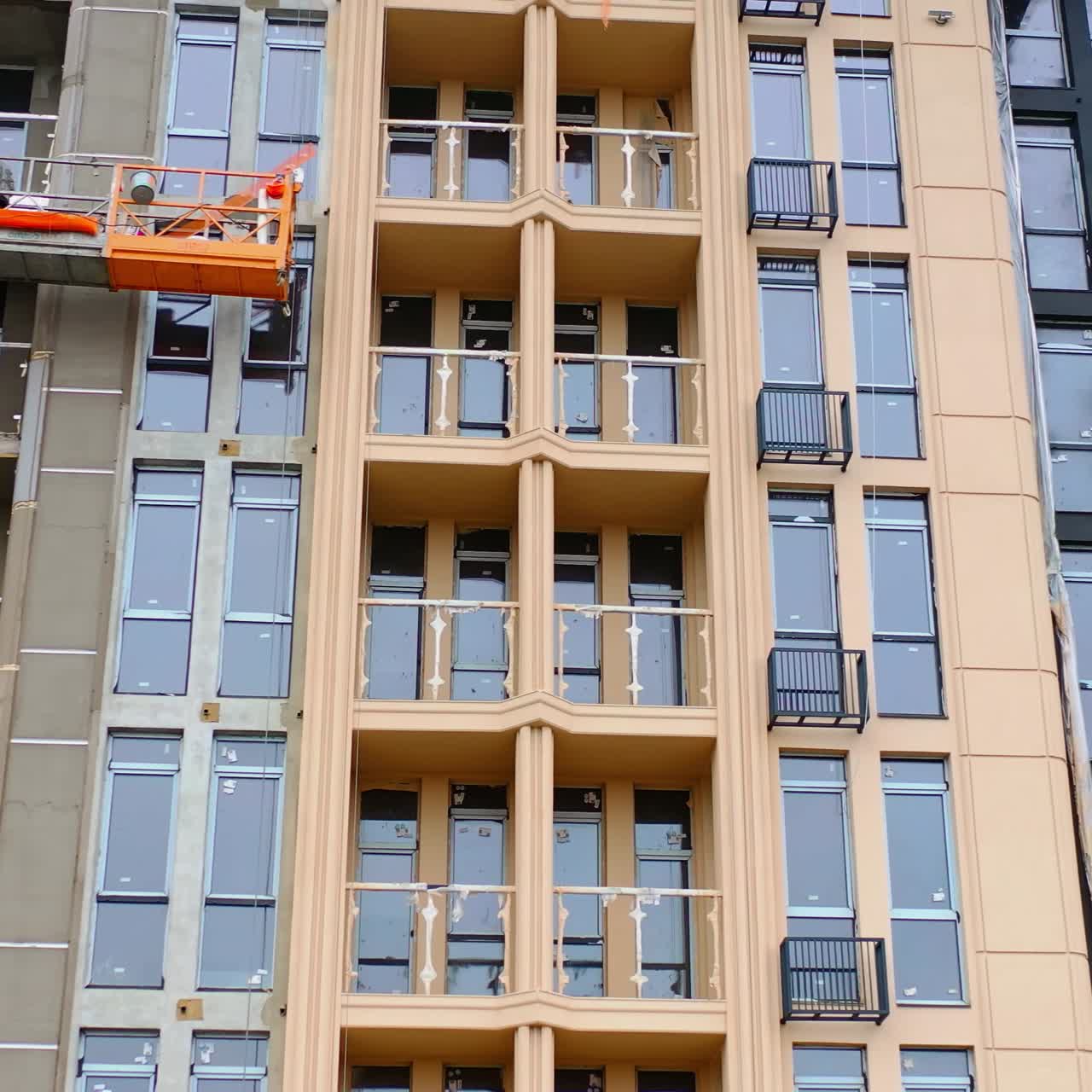 Front view of a new modern building. Construction of a high-rise apartment. Workers doing the outdoor view of a multistorey building.