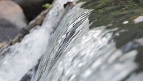 detailed view of water smoothly cascading over rocks in slow motion, showcasing movement, texture, and the beauty of a natural stream.