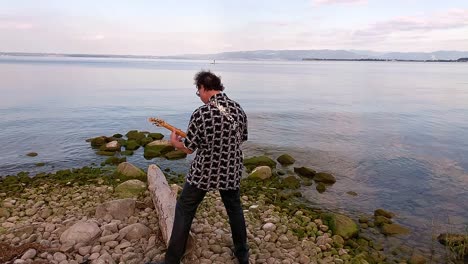 a man playing white guitar on the shore of the lake