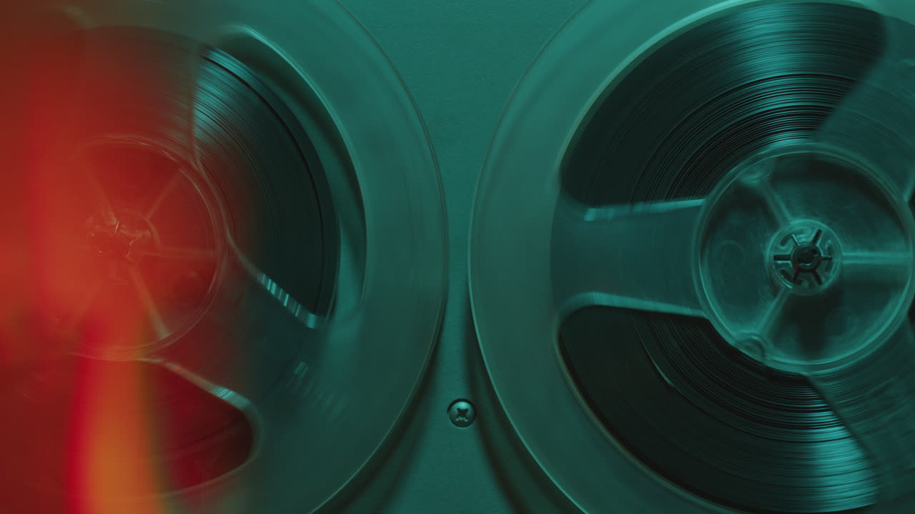 Rotating Reels of Old Analog Tape Recorder in Blue Neon Light