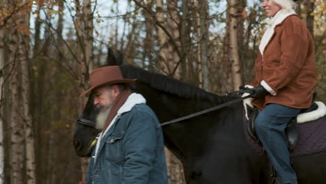 vrouw zit op een paard bij het bos.