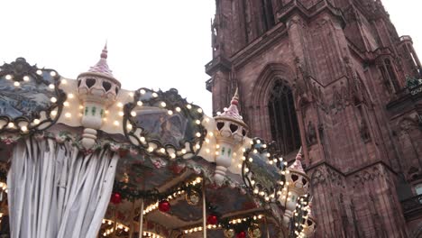 old traditional carousel spinning around in front of strasbourg cathedral and steeple at a festive christmas market in europe