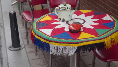 a table with a colorful tablecloth and a teapot