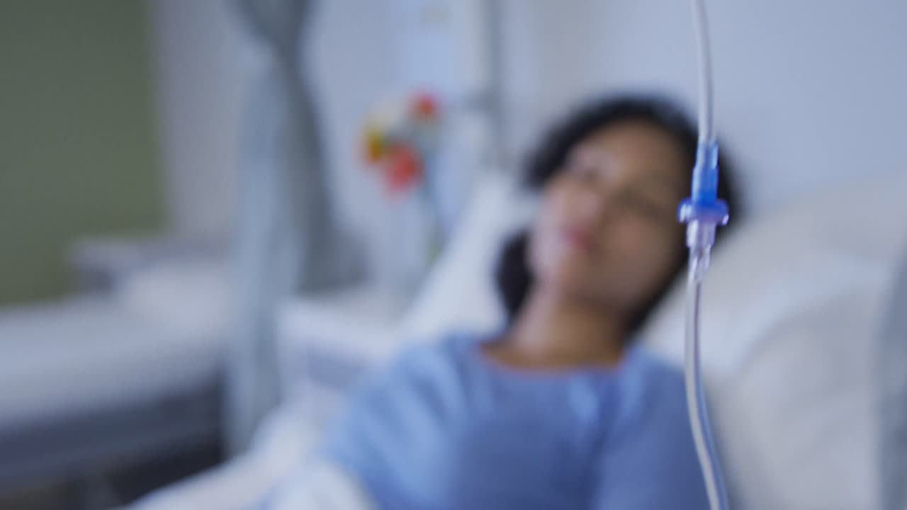 paciente de raza mixta acostada en la cama con un oxímetro de pulso en la punta del dedo y recibiendo goteo