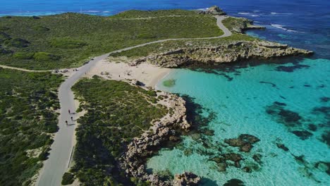 Aerial-view-of-cyclists-riding,-in-Salmon-Bay,-Rottnest-Island,-Australia--reverse,-drone-shot