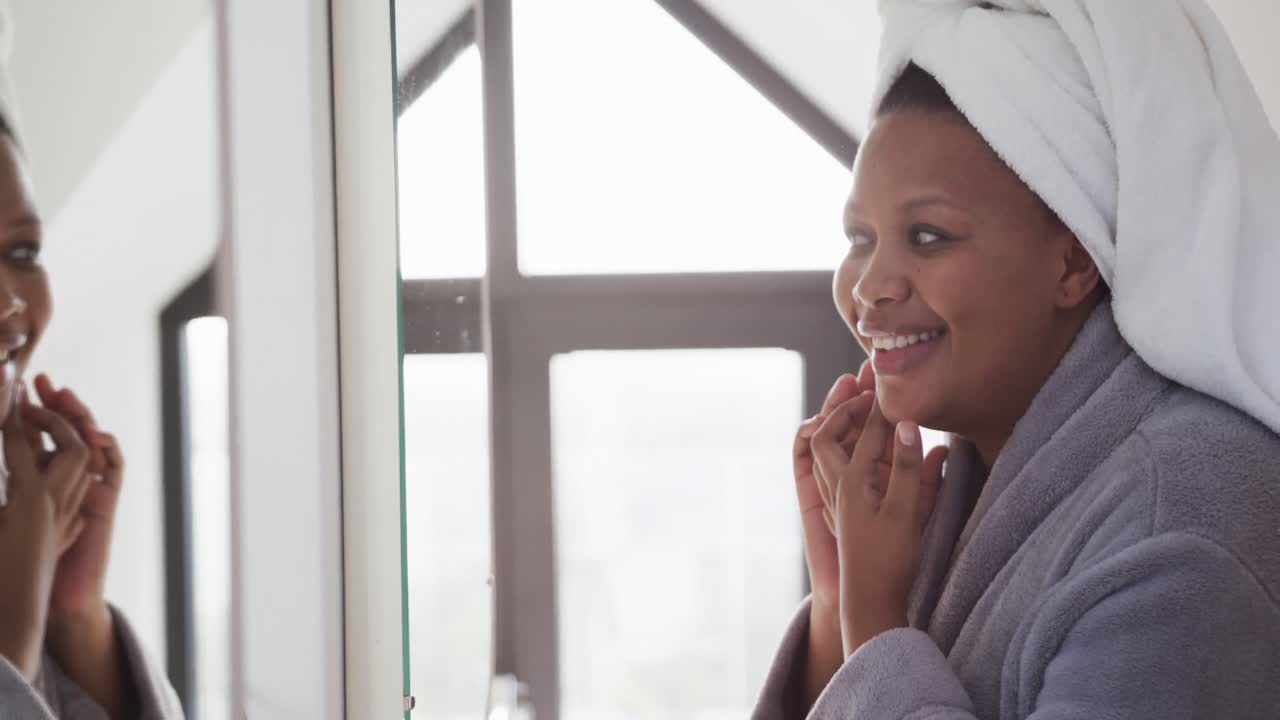 African american plus size woman looking in mirror and touching face, unaltered, slow motion