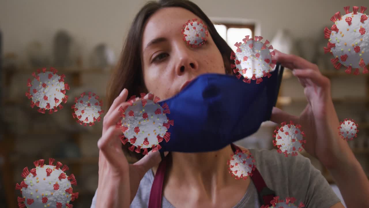 animación de células de covid-19 sobre una mujer que trabaja en un estudio de cerámica poniendo una máscara facial
