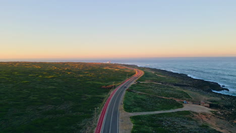 top view coastline road running along beautiful ocean at evening. aerial sunset