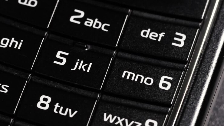 Rotating close up of black flip phone keypad with number and letter buttons