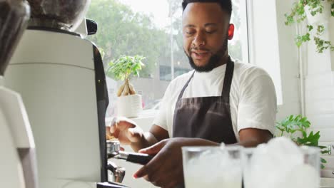 barista afroamericano feliz haciendo café usando una máquina de café en una cafetería