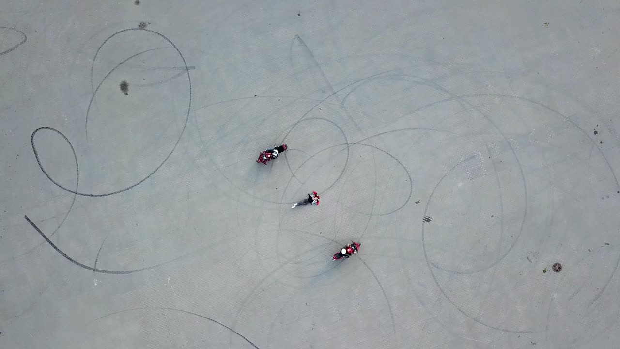 Biker riding around girl. Aerial drone shot of motorcycle riding in the middle of parking