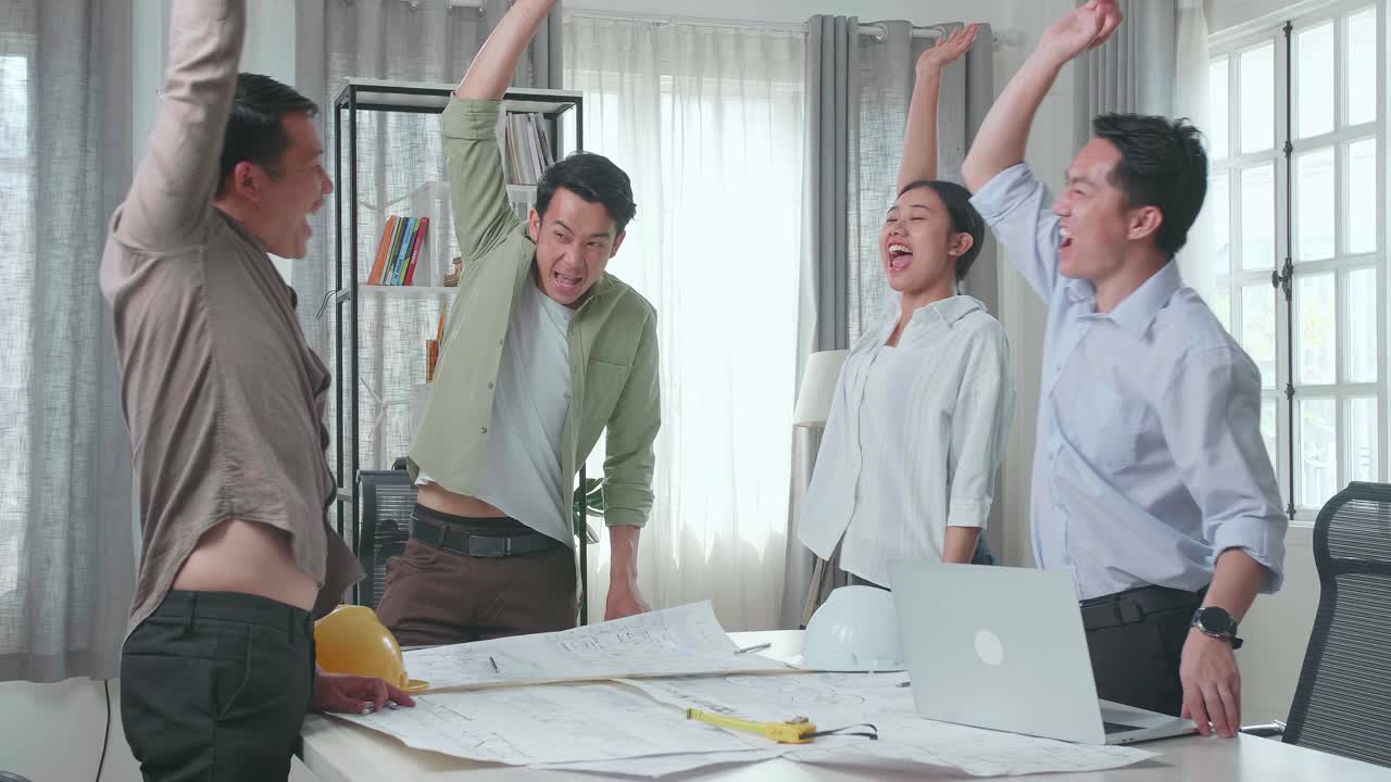 Group Of Asian Engineers Create Harmony With Hands On Top Of Each Other At The Office