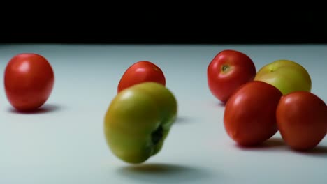 Red,-Green-and-yellow-tomatoes-fall-and-roll-on-table,-slow-motion