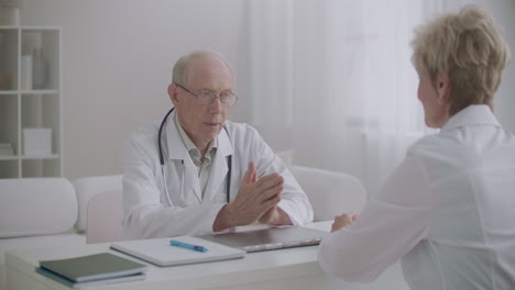 dos médicos están hablando en el consultorio médico en el hospital discutiendo sentarse a la mesa uno contra el otro concilium