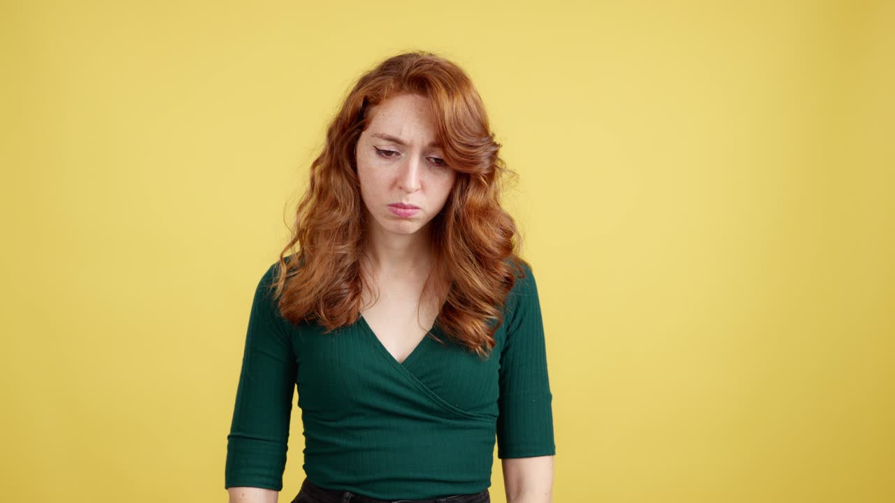 Emotional Red-Haired Woman Expressing Sadness and Disappointment on Yellow Background