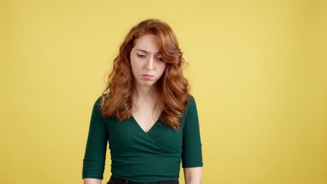 emotional red-haired woman expressing sadness and disappointment on yellow background