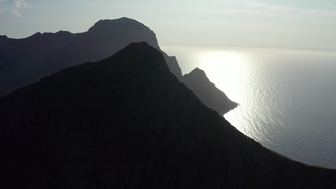 Ripresa con drone delle silhouette di ripide scogliere e montagne delle Lofoten che si ergono dal mare blu profondo.