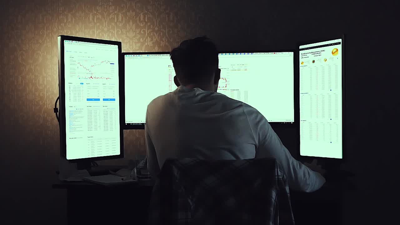 persona que trabaja tarde en la noche en múltiples monitores de computadora