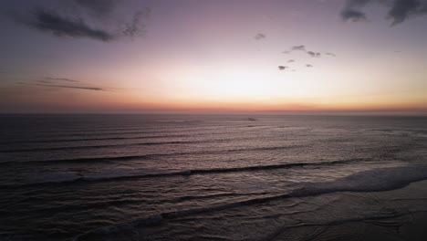 4k aerial drone over ocean waves with sunset on horizon