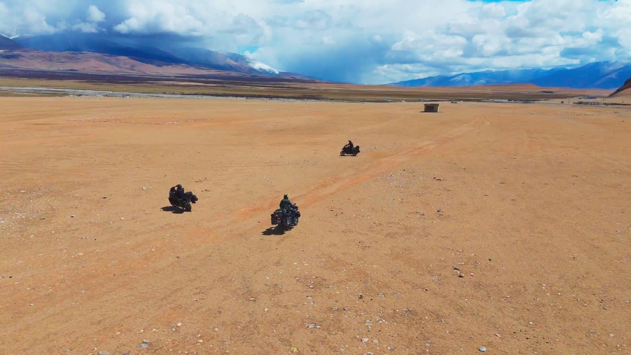 ground of adventure motorcycle rider riding in red sand desert with mountains snow capped inn background