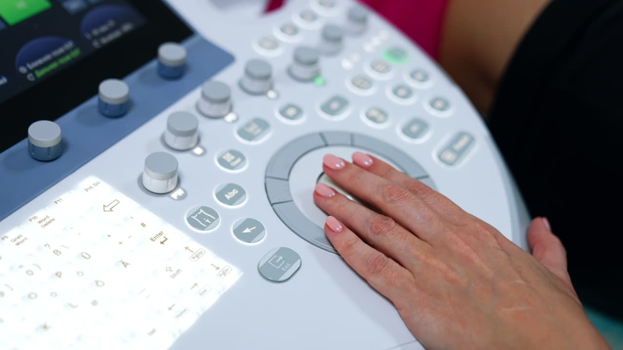 Female medic's hand on the keyboard of ultrasound machine. Doctor is pressing some buttons on the apparatus. Close up.