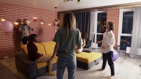 Group-of-people-at-living-room-playing-with-balloon,-have-fun-together