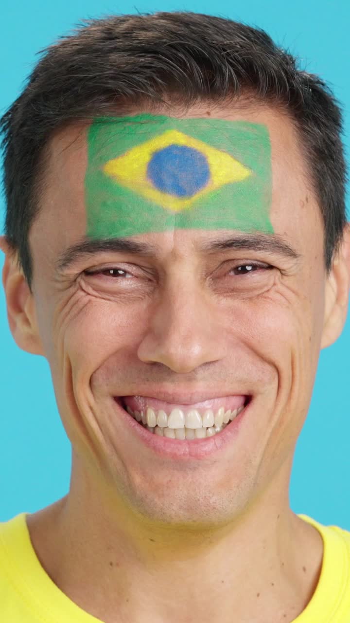 Man with a brazilian flag painted on the face smiling
