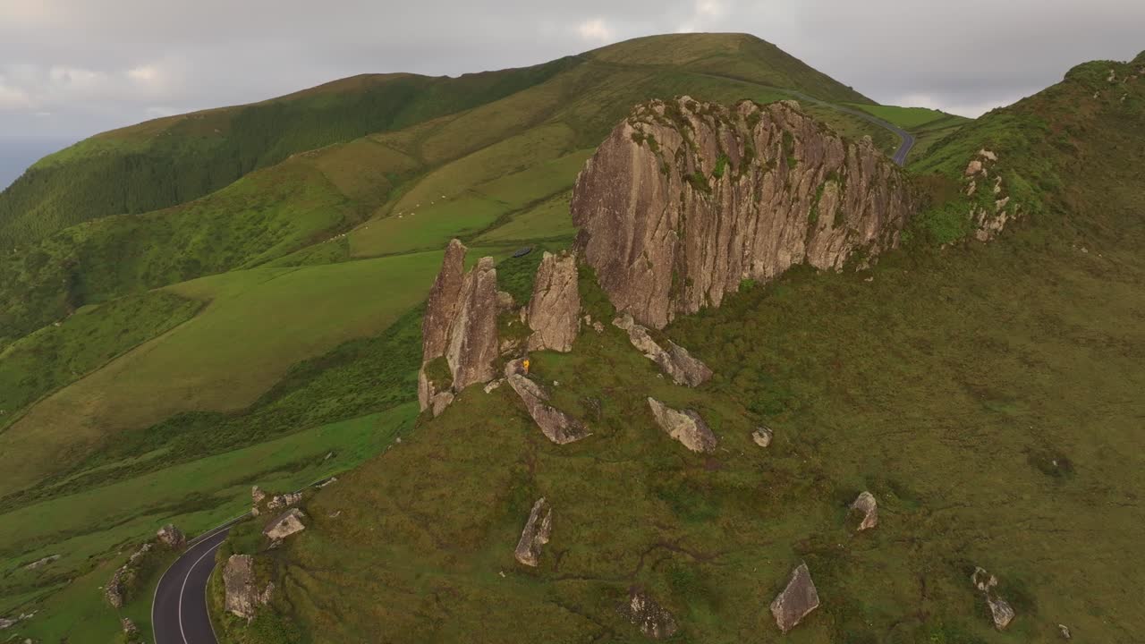 Luftaufnahme einer üppig grünen Landschaft und felsiger Klippen bei Rocha dos Frades bei Sonnenaufgang auf der Insel Flores.