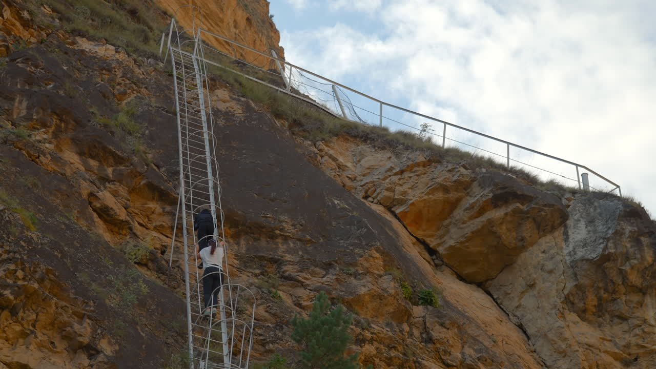 People climbing a ladder on a cliff
