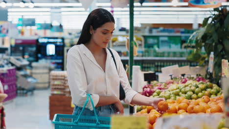 woman shopping for oranges in a grocery store