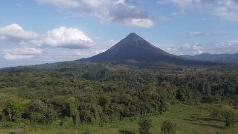 aerial over rural homes and dense jungle to arenal volcano beyond