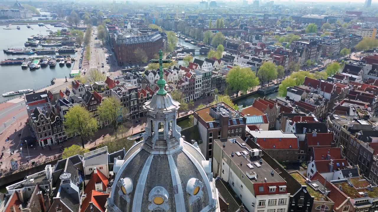 Kinoreifer Drohnenflug über dem Dach der historischen Basilika des Heiligen Nikolaus, der die wunderschöne Skyline von Amsterdam und traditionelle niederländische Gebäude in einer Panorama-Luftaufnahme enthüllt.