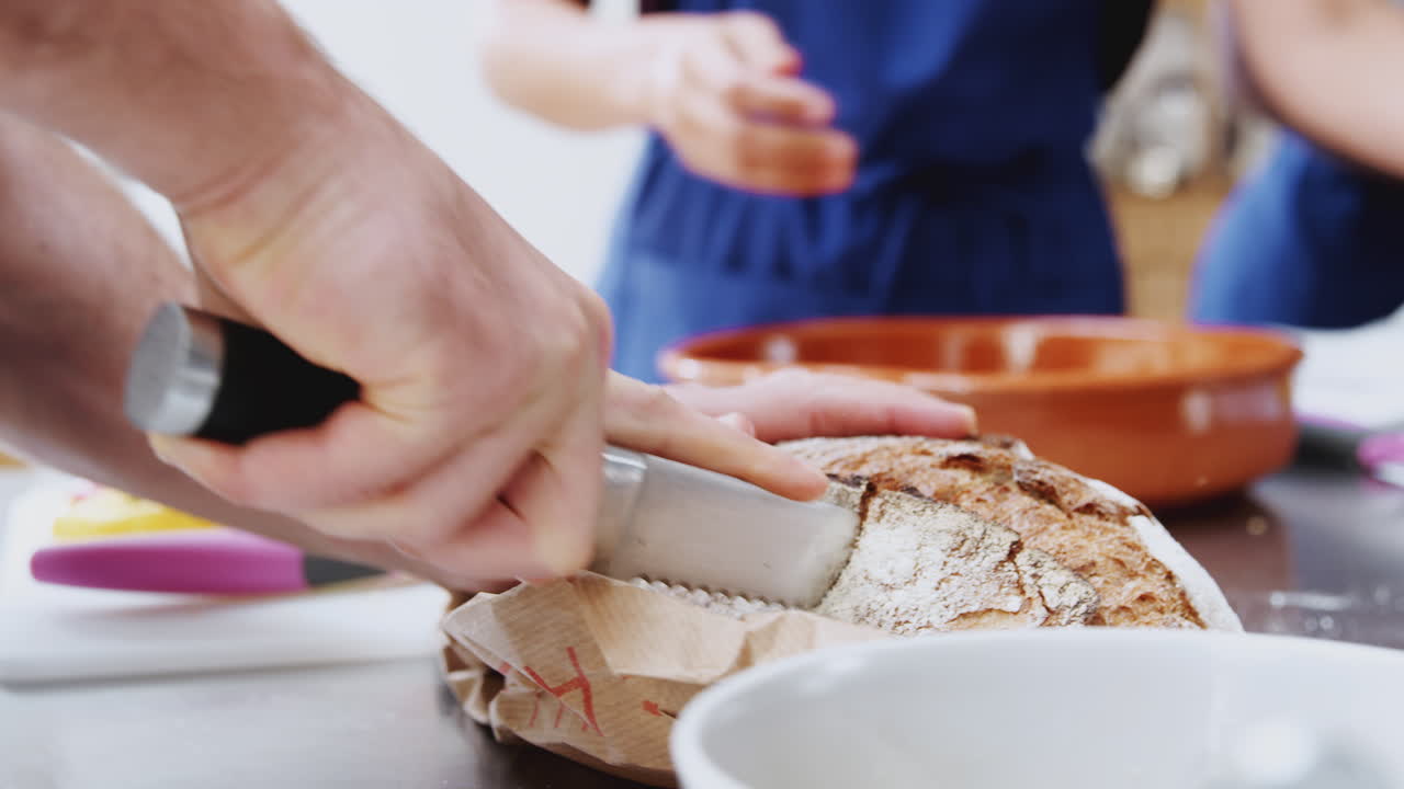 Close Up Of Man Slicing Bread For Dish In Kitchen Cookery Class