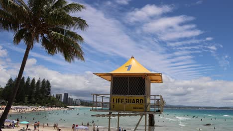 crowded beach scene with lifeguard tower and swimmers